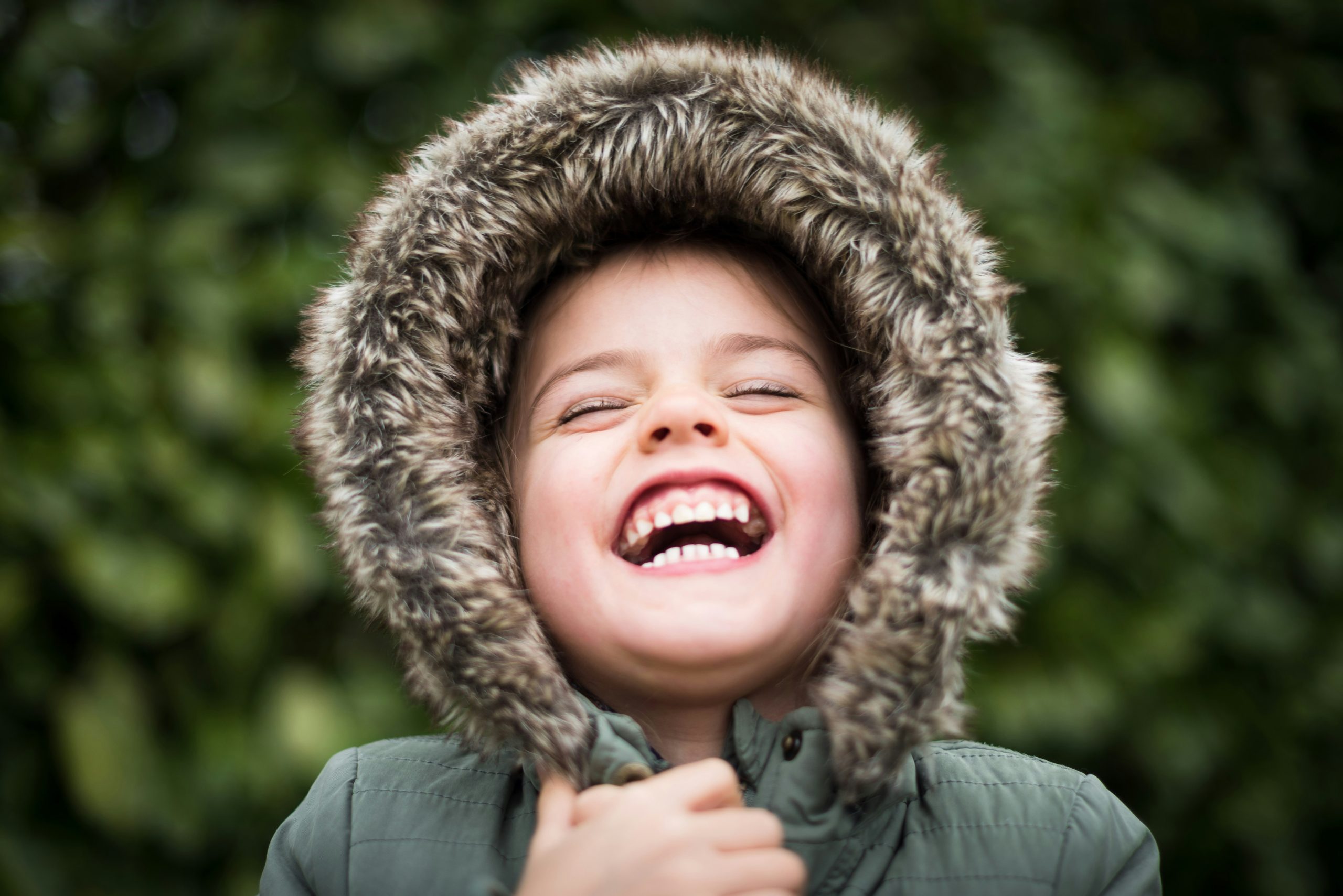 Child laughing in fuzzy coat.