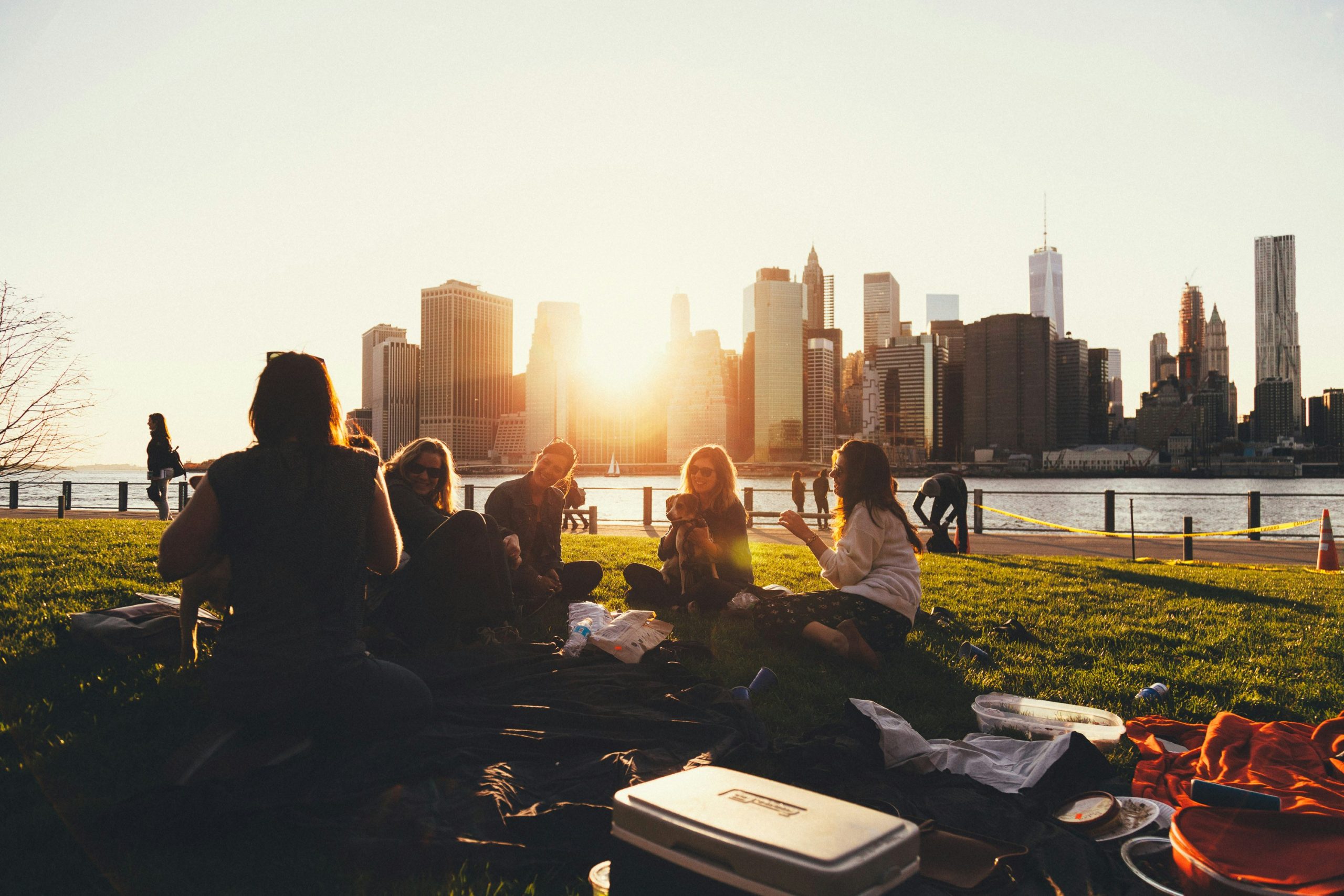 Group of women having a picnic near waterfront, across from a city.