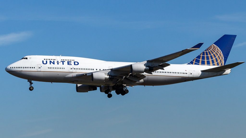 A photograph of a United jumbo-jet airplane flying on a blue sky background.