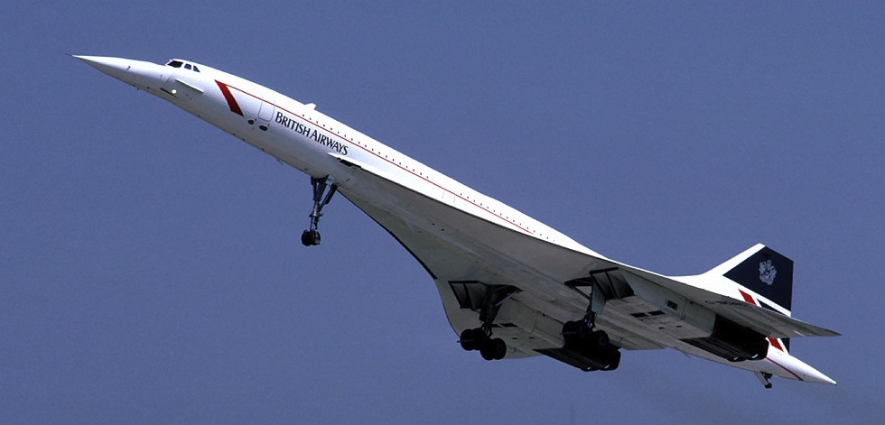 Photograph of a white aircraft flying towards the upper left on a blue sky background. British Airways is written on the fuselage.