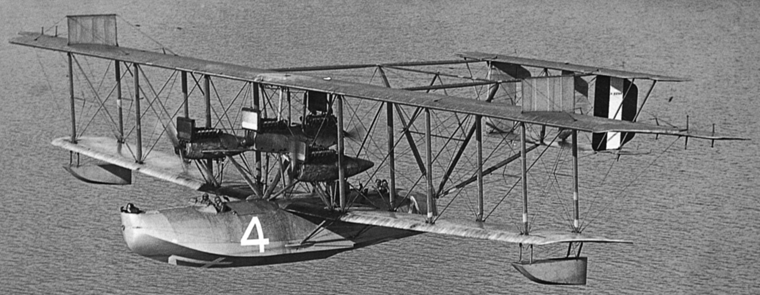 A black and white photograph of a biplane with a white 4 painted on the fuselage.