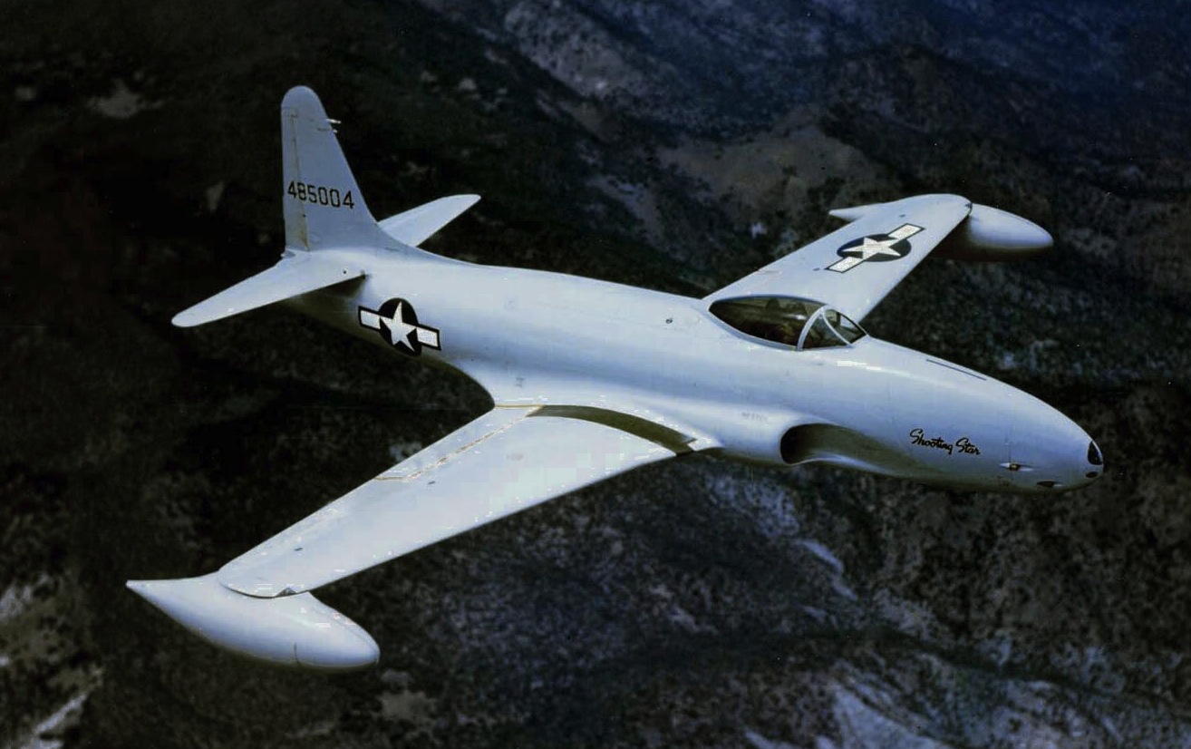 A photograph of a white airplane with stars on the fuselage and and turbojet engines mounted under the bottom of the wingtips.