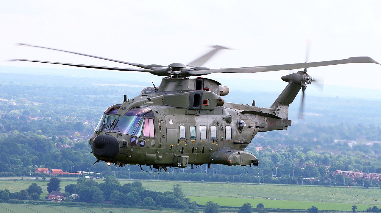 A photograph of a large military helicopter flying over a rural area.