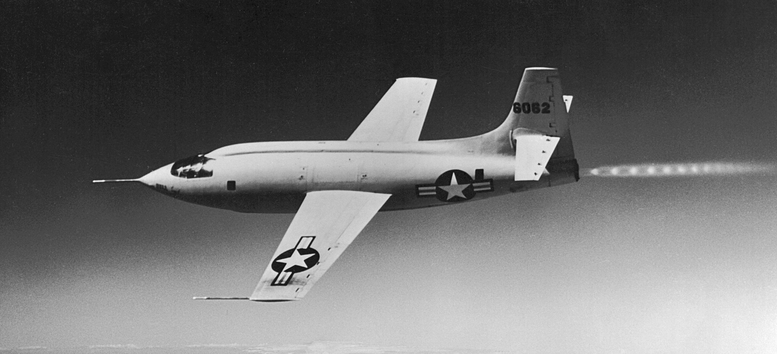 A black and white photograph of an aircraft with stars on the wing and fuselage. It has a distinctive pointed nose and visible afterburner diamonds behind the engine.