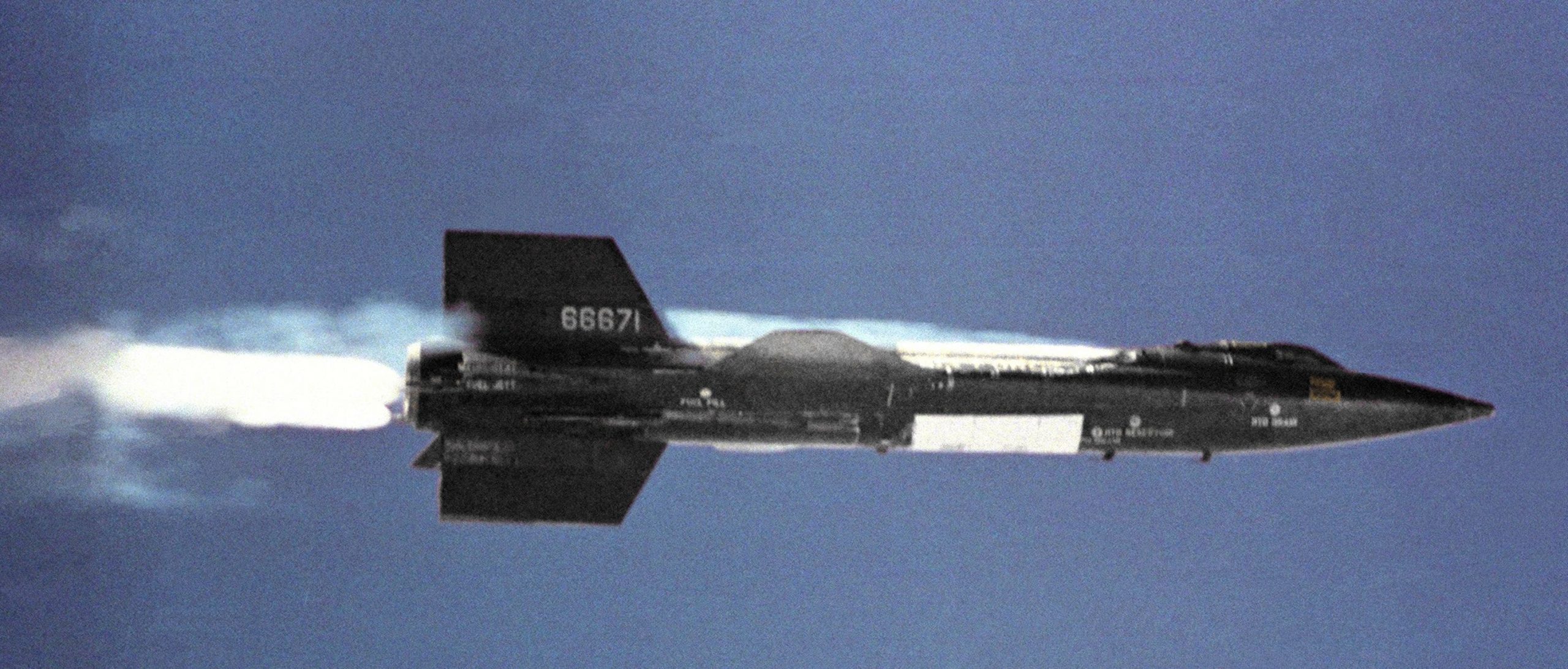 A photograph of a black aircraft on a dark blue backdrop.